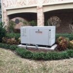 27kw Whole home standby generator installed in a landscaped front yard.