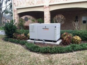 27kw Whole home standby generator installed in a landscaped front yard.