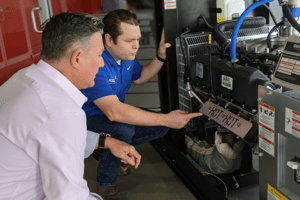 Generator technician explaining standby generator components to a homeowner