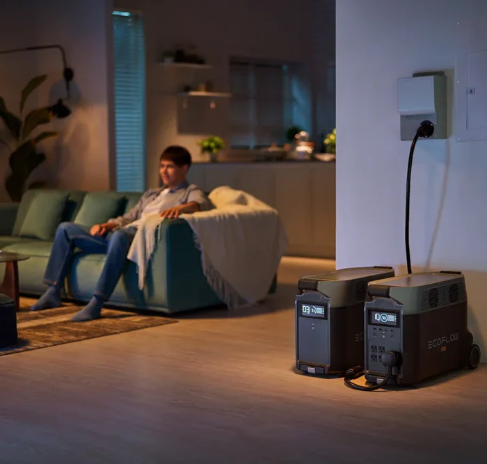 Man on sofa during a nighttime power outage with emergency backup power nearby