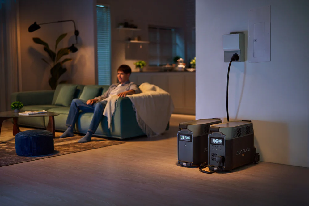 Man on sofa during a nighttime power outage with emergency backup power nearby