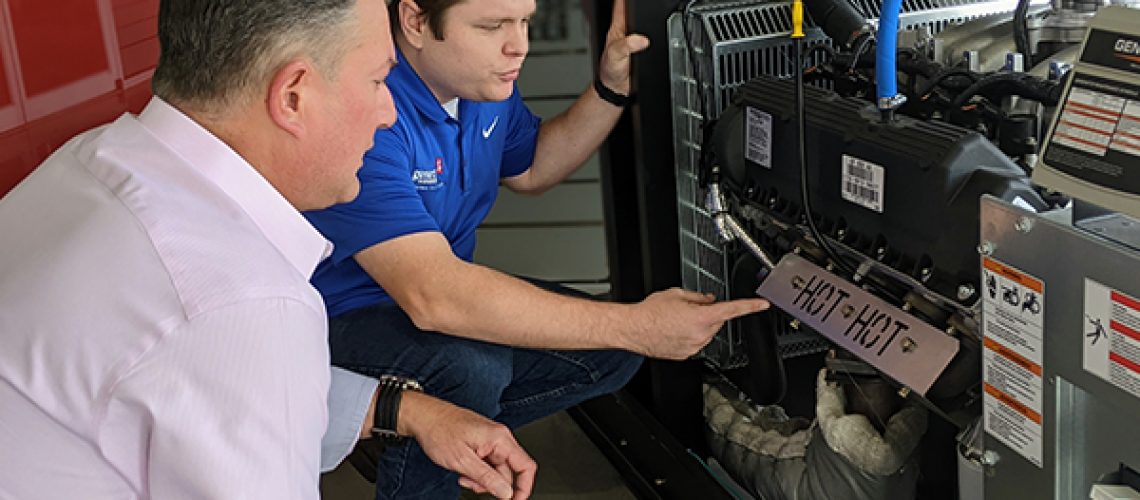 Generator technician explaining standby generator components to a homeowner